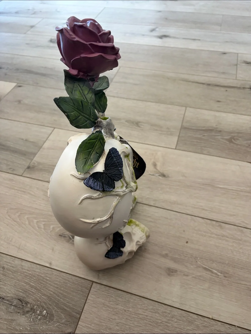 White Skull Statue with Green Moss, Rose, and Butterfly accents.